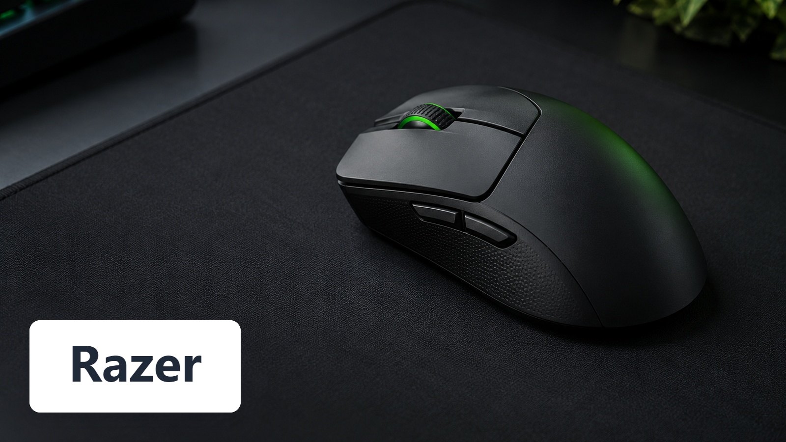 Razer name with Black wireless gaming mouse with green-lit scroll wheel on dark mouse mat, keyboard behind